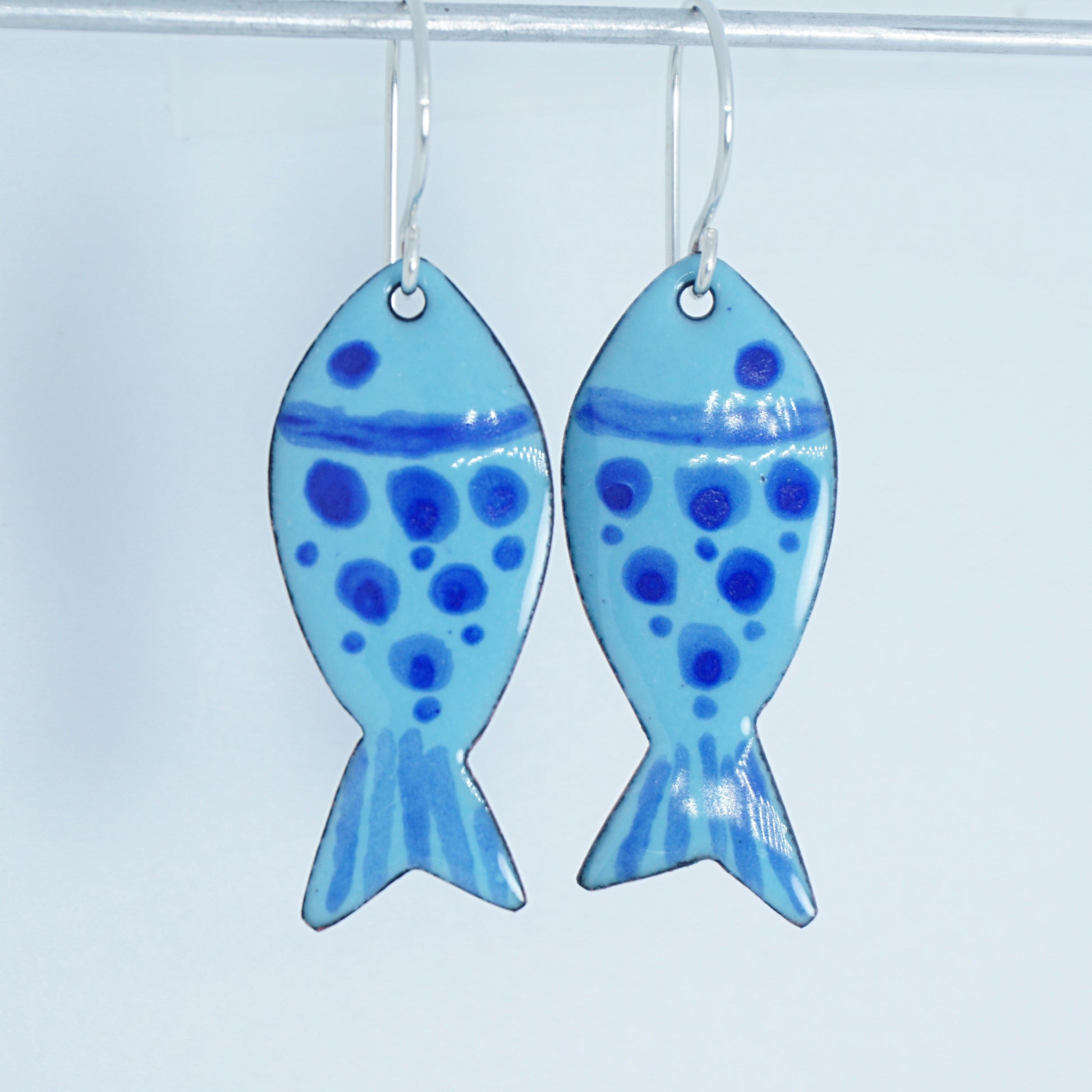 Pair of fish-shaped earrings with blue pattern on a white background