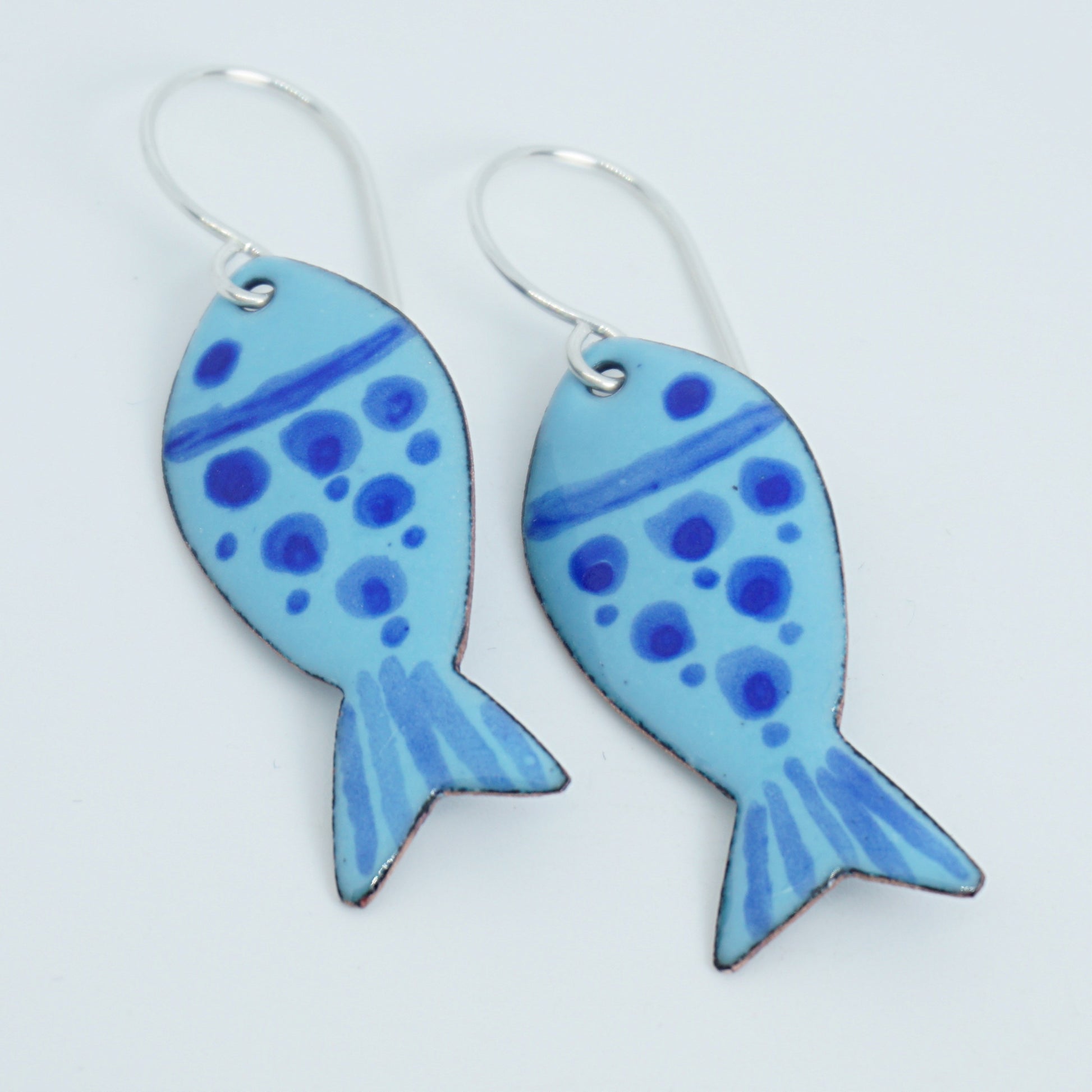 Pair of blue fish-shaped earrings on a white background