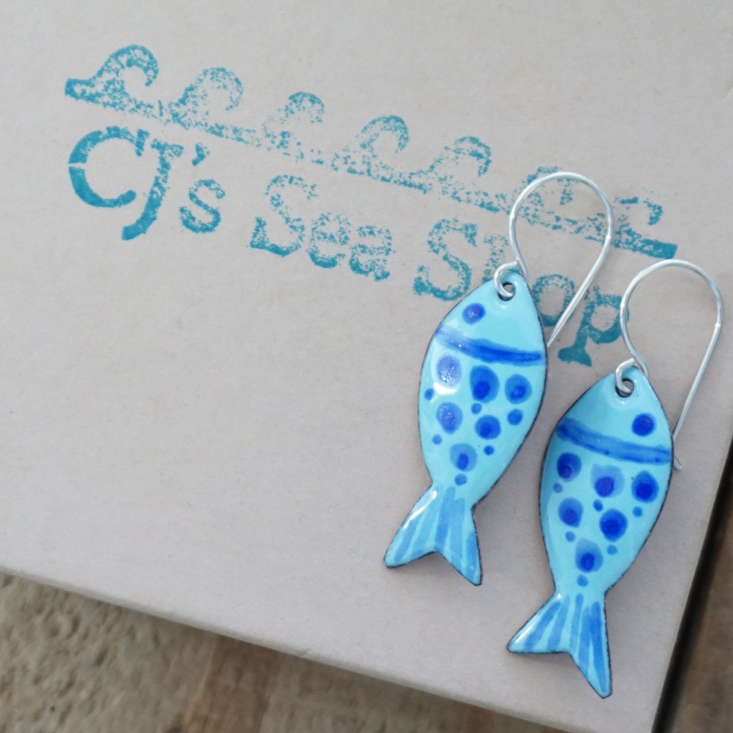 Blue fish-shaped earrings on a gift box