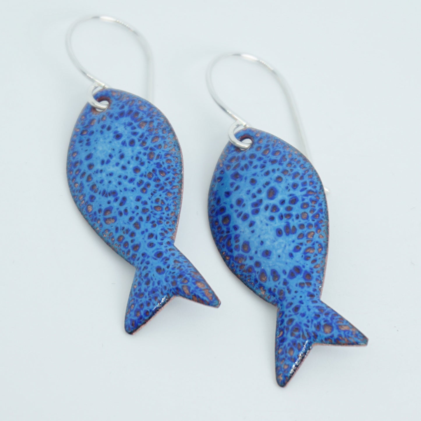 Blue spotted fish-shaped earrings on a white background