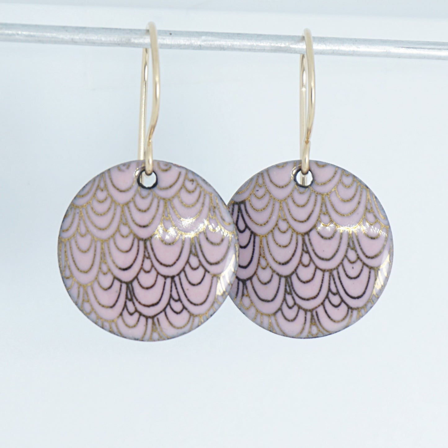 pink disc shaped earrings with gold accents on a white background