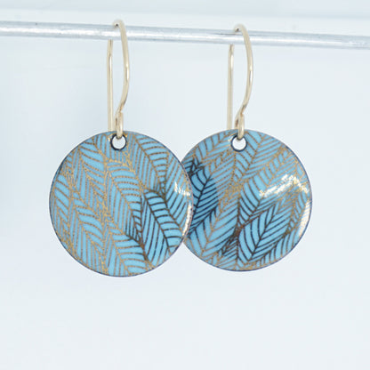 Pair of blue round earrings with leaf pattern on a white background