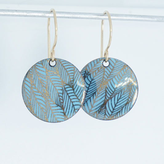 Pair of blue round earrings with leaf pattern on a white background