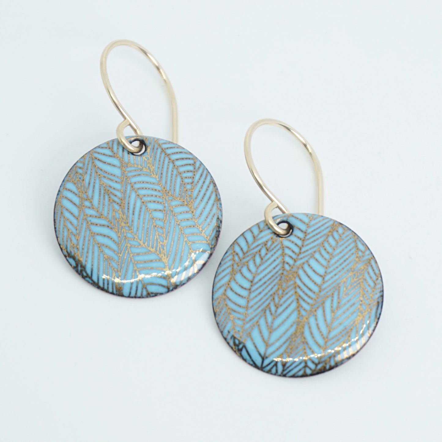 Pair of blue and gold leaf patterned earrings on a white background