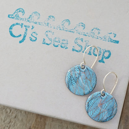Blue and gold leaf patterned earrings on a gift box