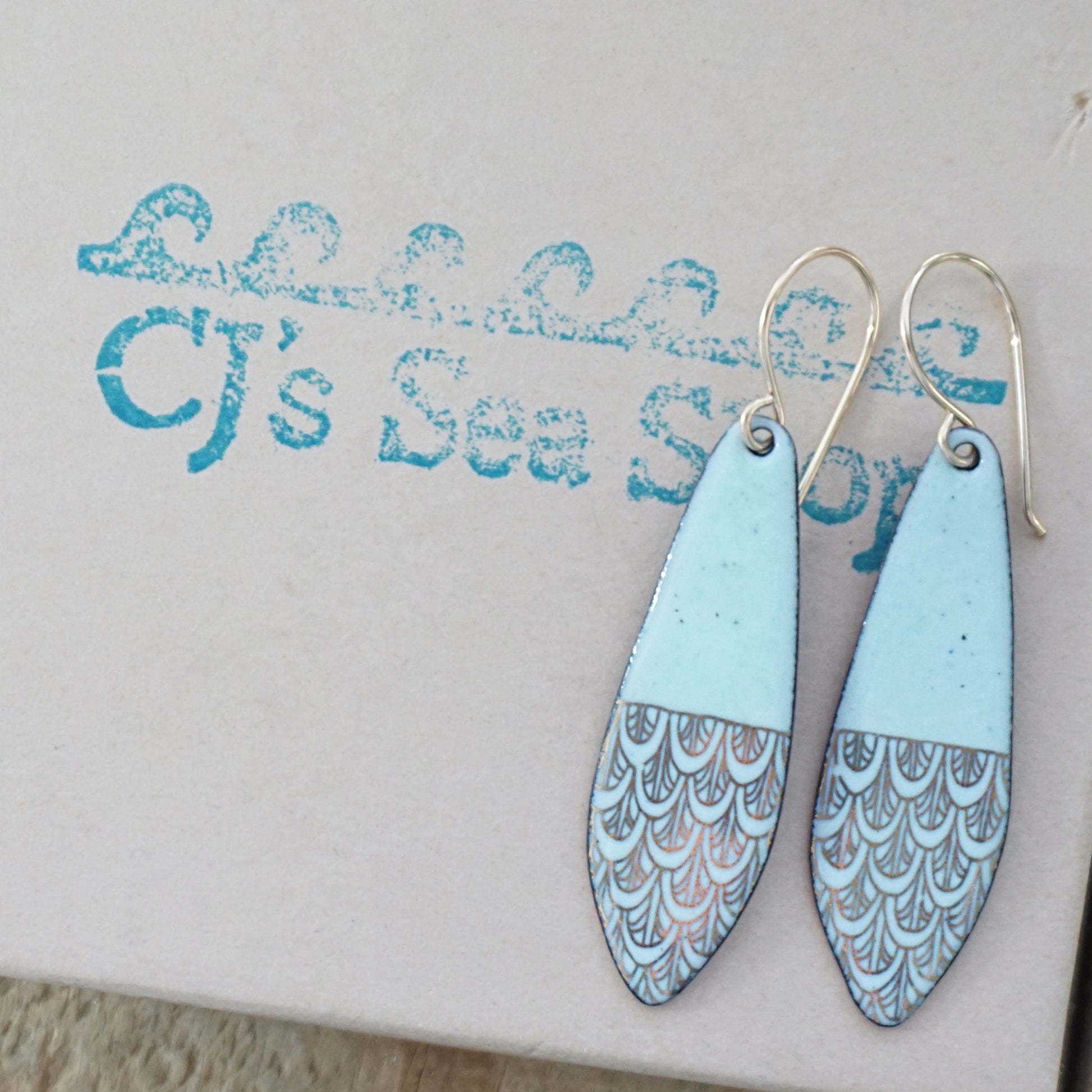 Green and gold patterned earrings on a gift box