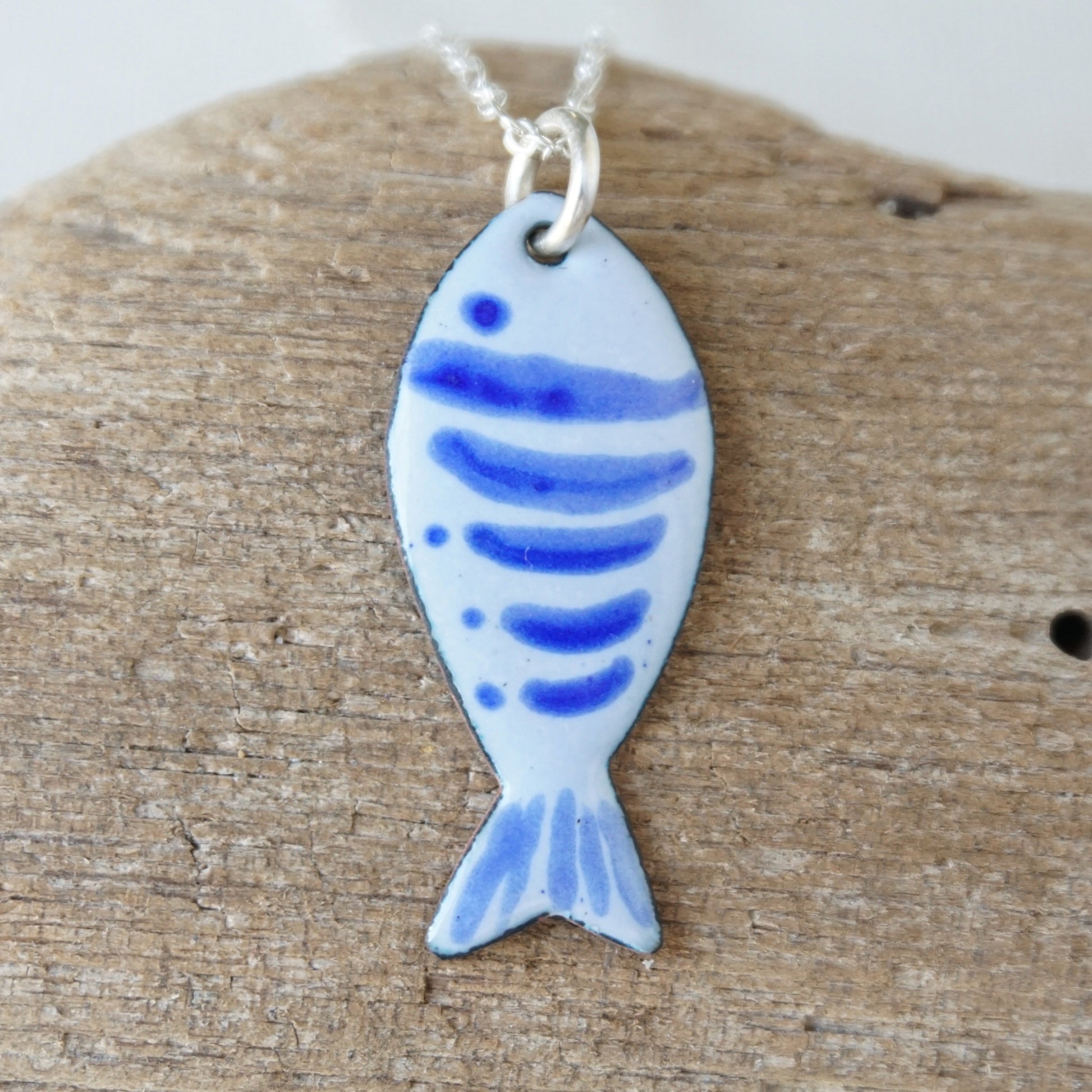 Fish-shaped pendant with blue patterns on a wooden surface