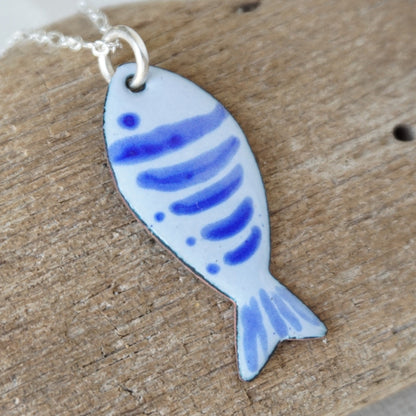 Blue fish-shaped pendant on a wooden surface