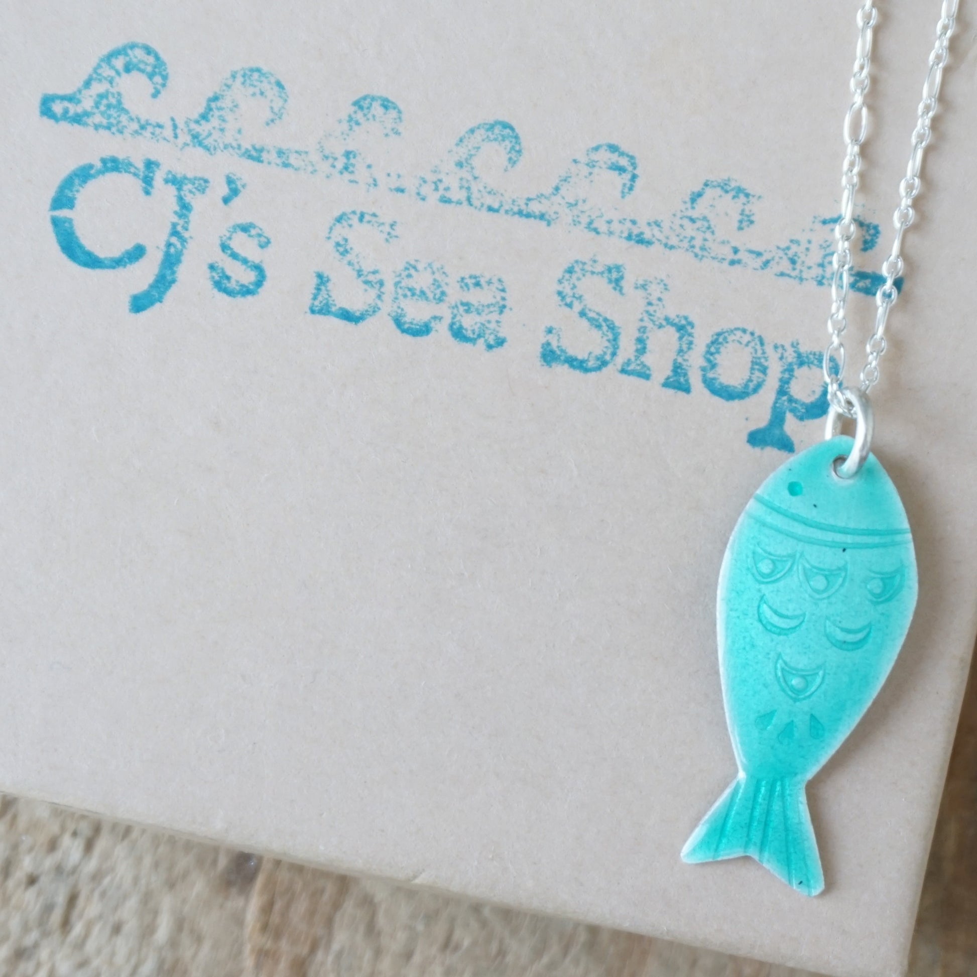 Green fish pendant necklace on a gift box