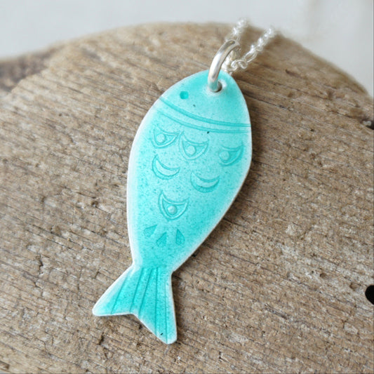 Green fish-shaped pendant on a wooden surface