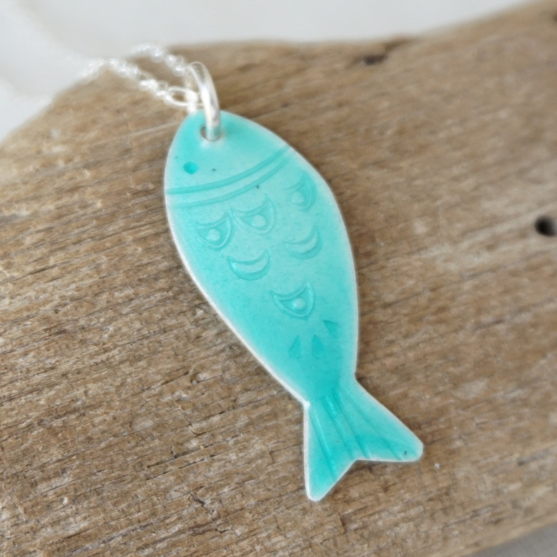 Green fish-shaped pendant on a wooden surface