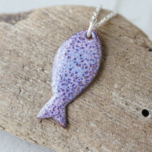 Purple speckled fish pendant on a silver chain on a wooden surface