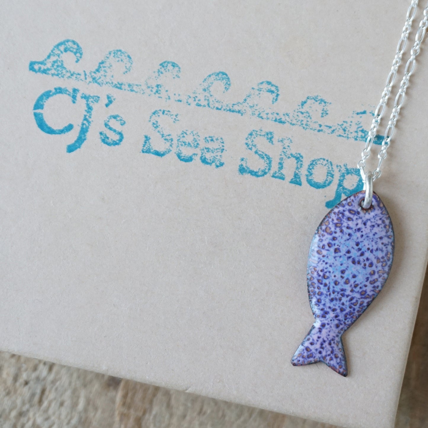 Purple fish-shaped pendant on a gift box