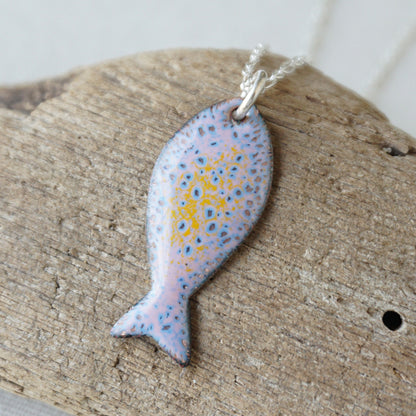 Fish-shaped pendant with a spotted pattern on a wooden surface