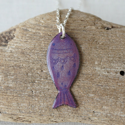 Purple fish-shaped pendant on a silver chain against a wooden background