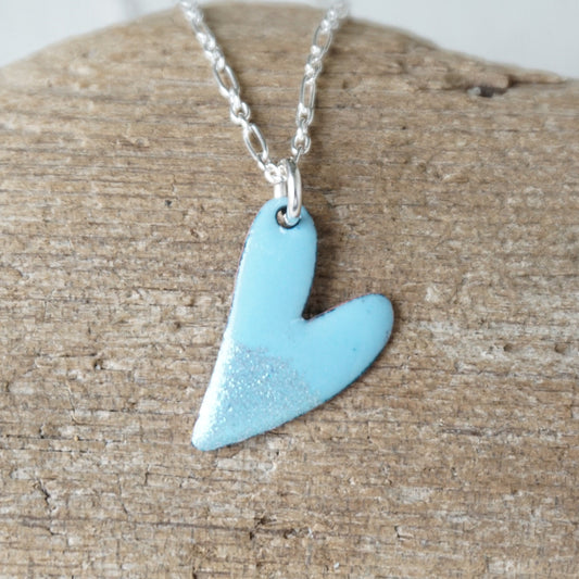 Blue heart-shaped pendant on a silver chain against a wooden background