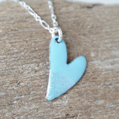 Blue heart-shaped pendant on a silver chain against a wooden background