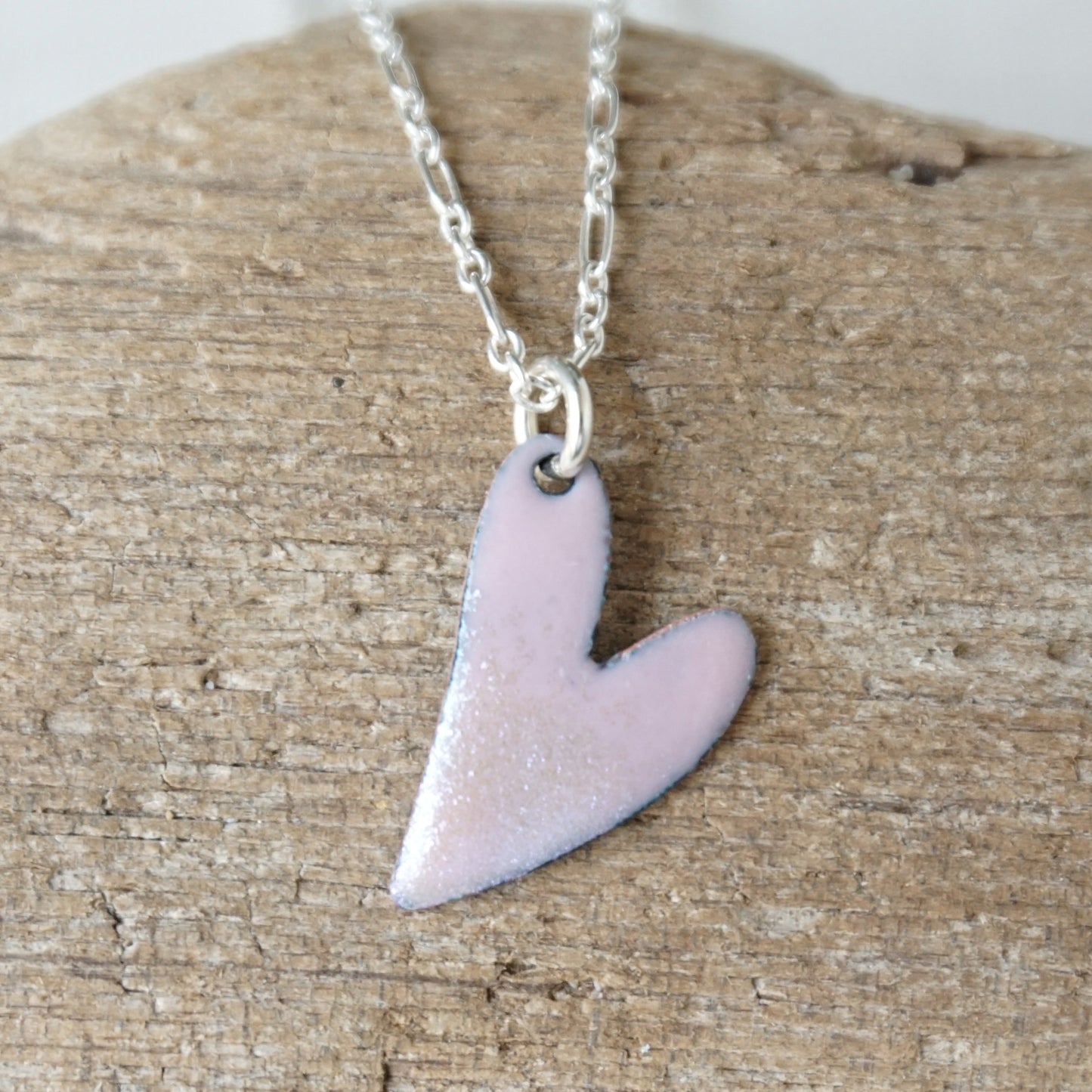 pink Heart-shaped pendant on a chain against a wooden background