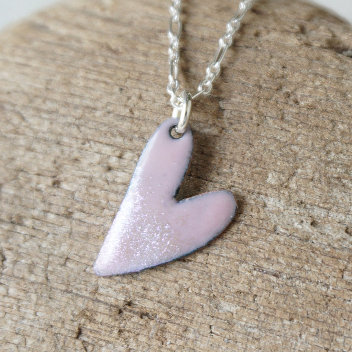 pink Heart-shaped pendant on a chain against a wooden background
