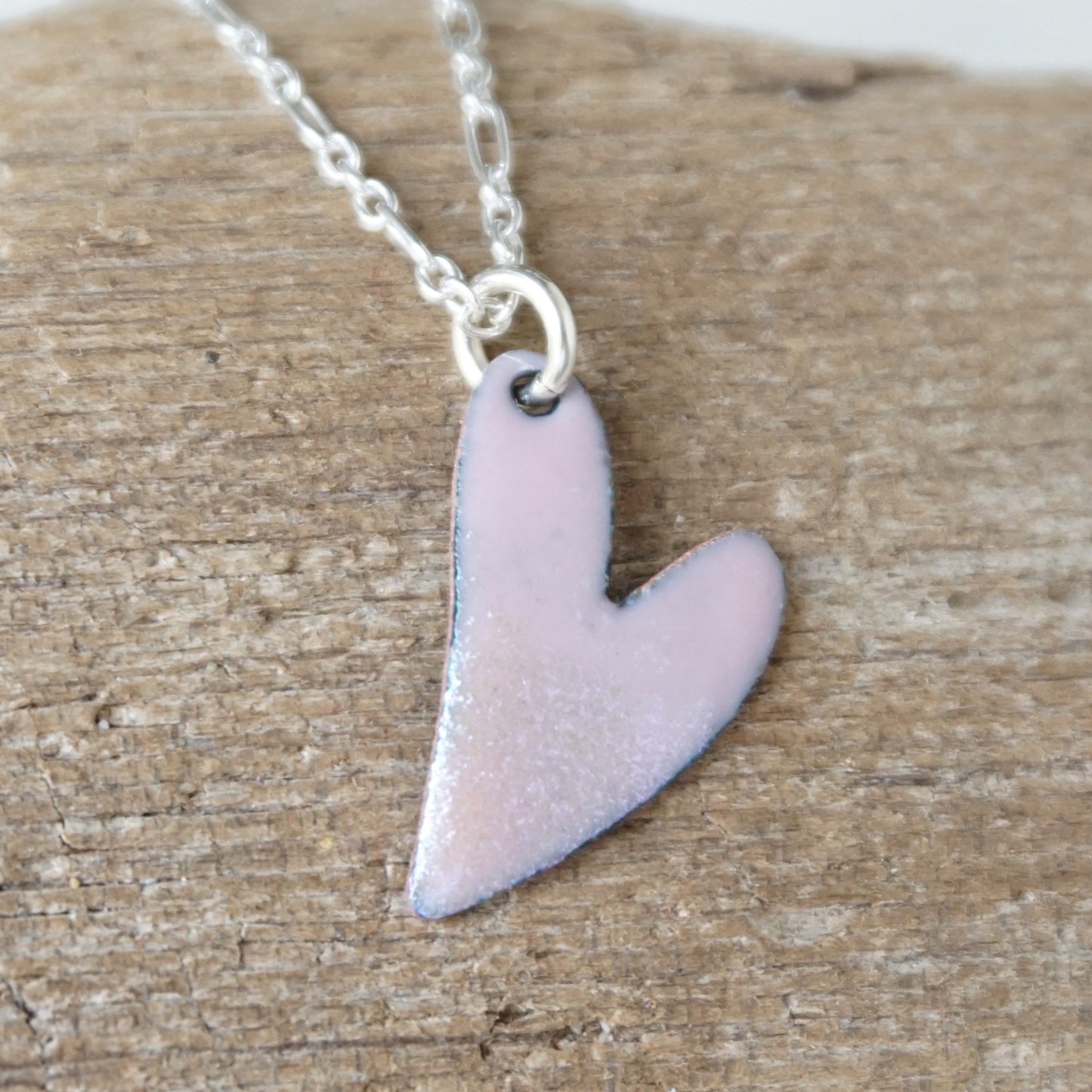 pink Heart-shaped pendant on a chain against a wooden background