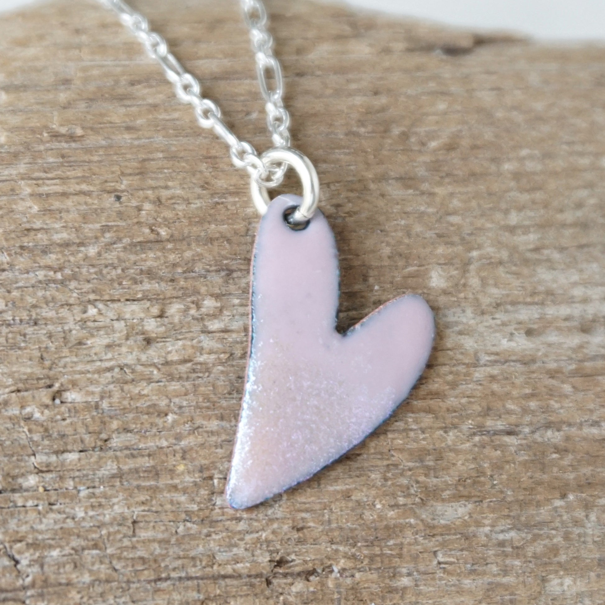 pink Heart-shaped pendant on a chain against a wooden background