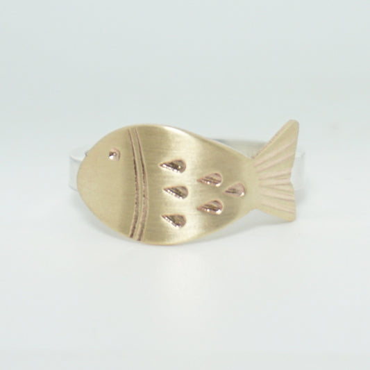 hand stamped brass fish on a silver ring, against a white background