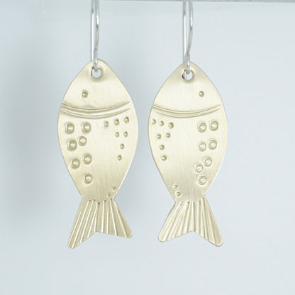 brass fish-shaped earrings on a white background