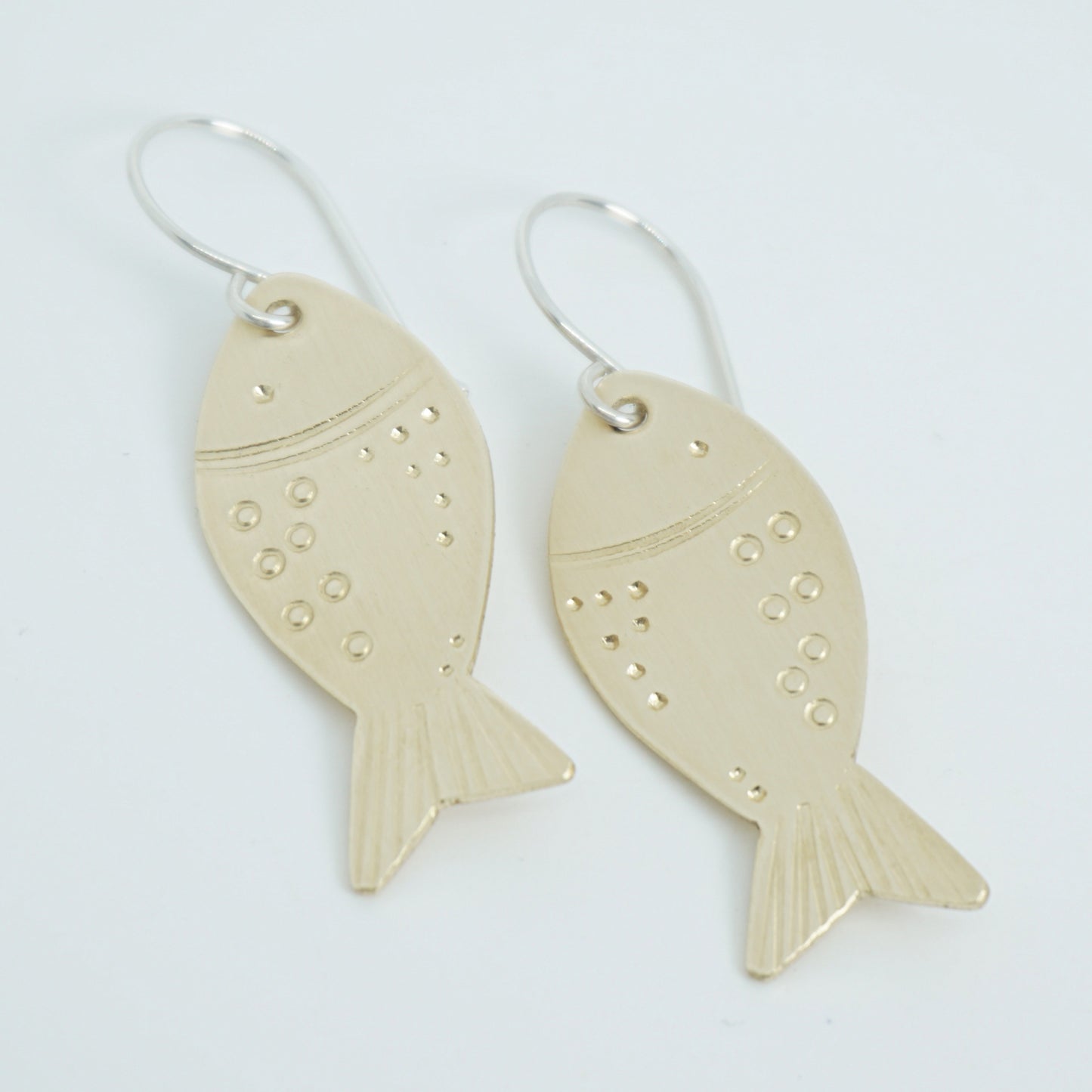 brass fish-shaped earrings on a white background
