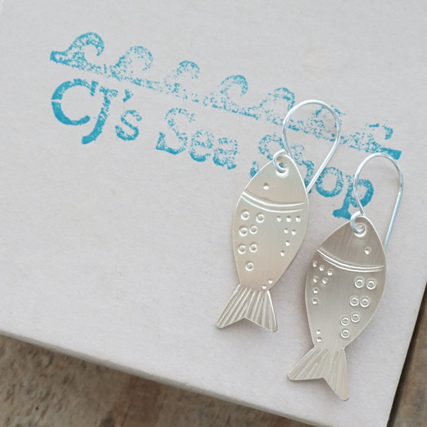 brass fish-shaped earrings on a gift box