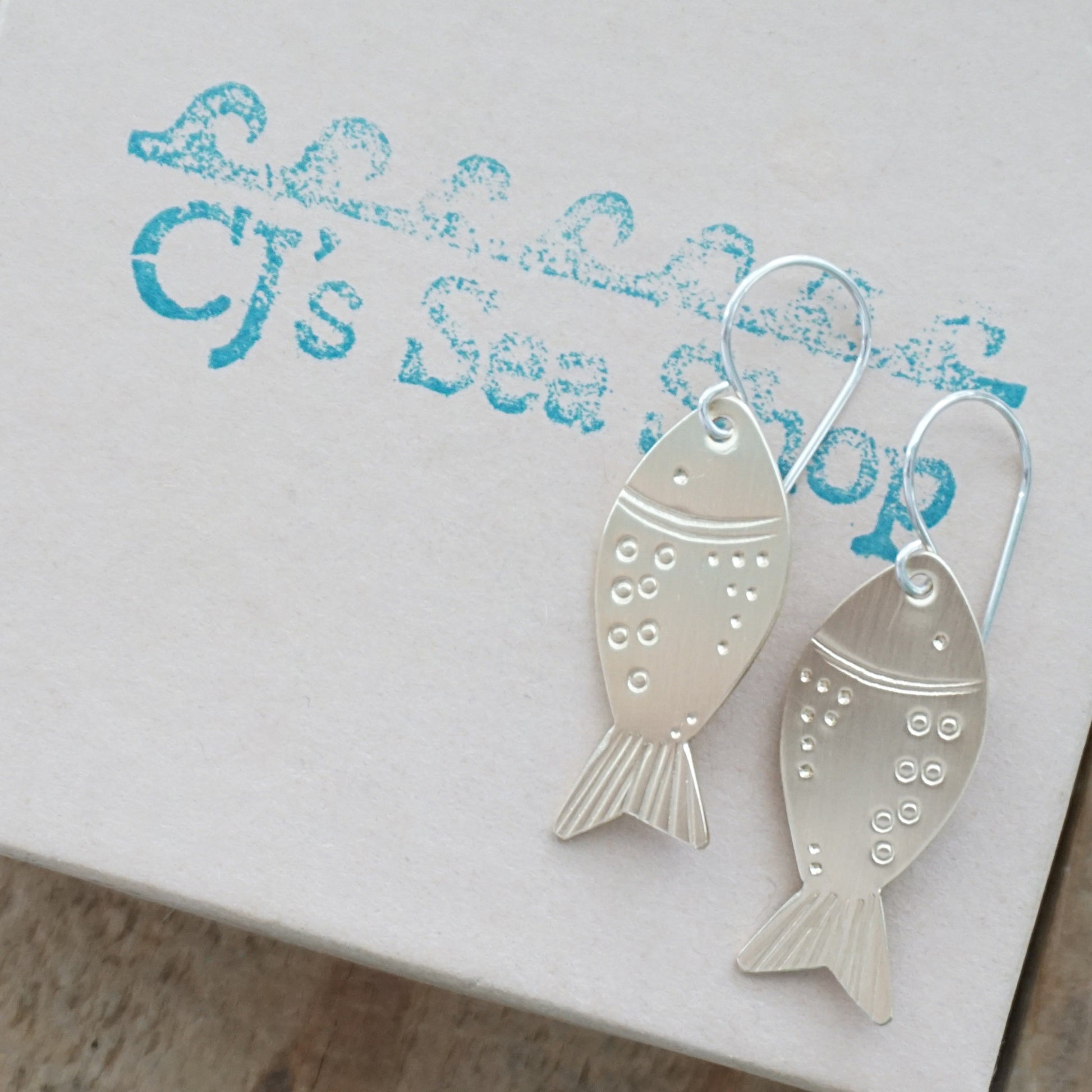 brass fish-shaped earrings on a gift box