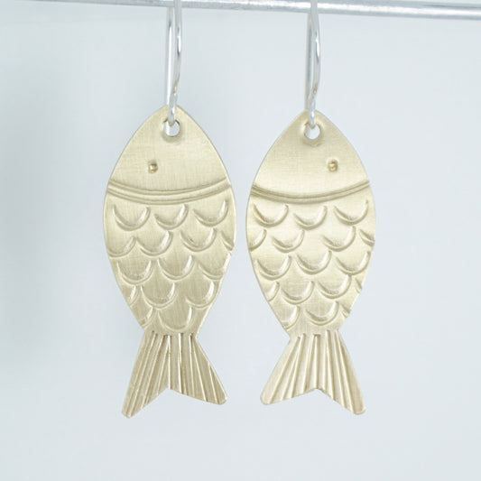 brass fish shaped earrings on a white background