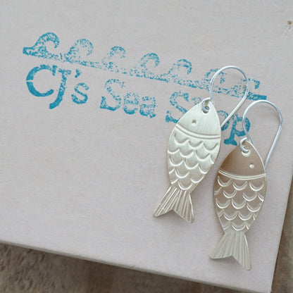 brass fish-shaped earrings on a gift box