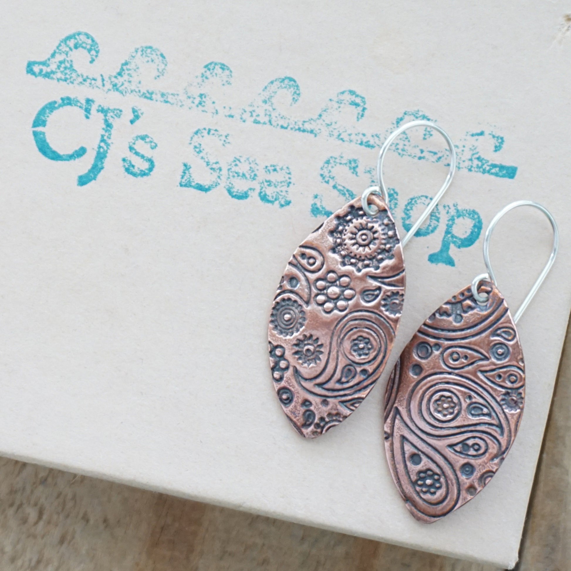 Pair of copper patterned earrings on a gift box