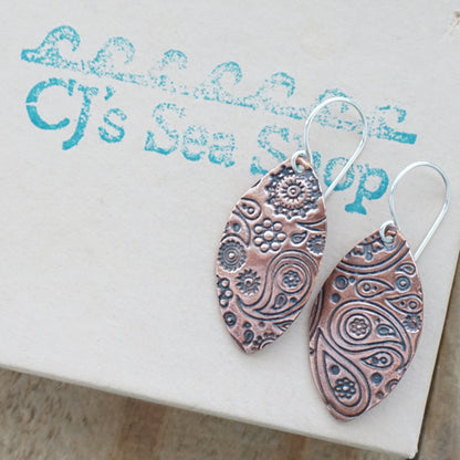 Pair of copper patterned earrings on a gift box