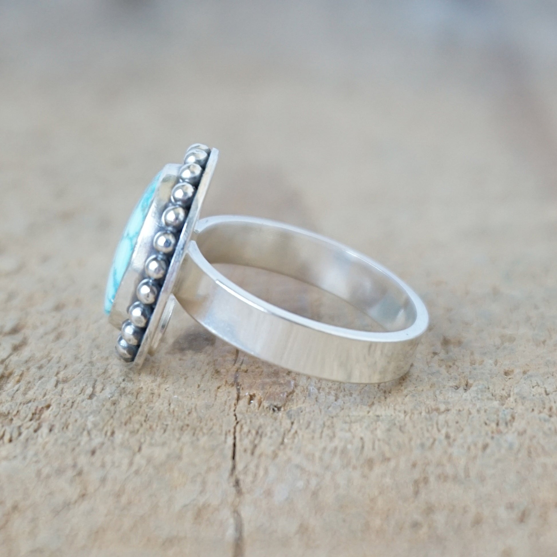 Silver ring with a turquoise stone on a wooden surface