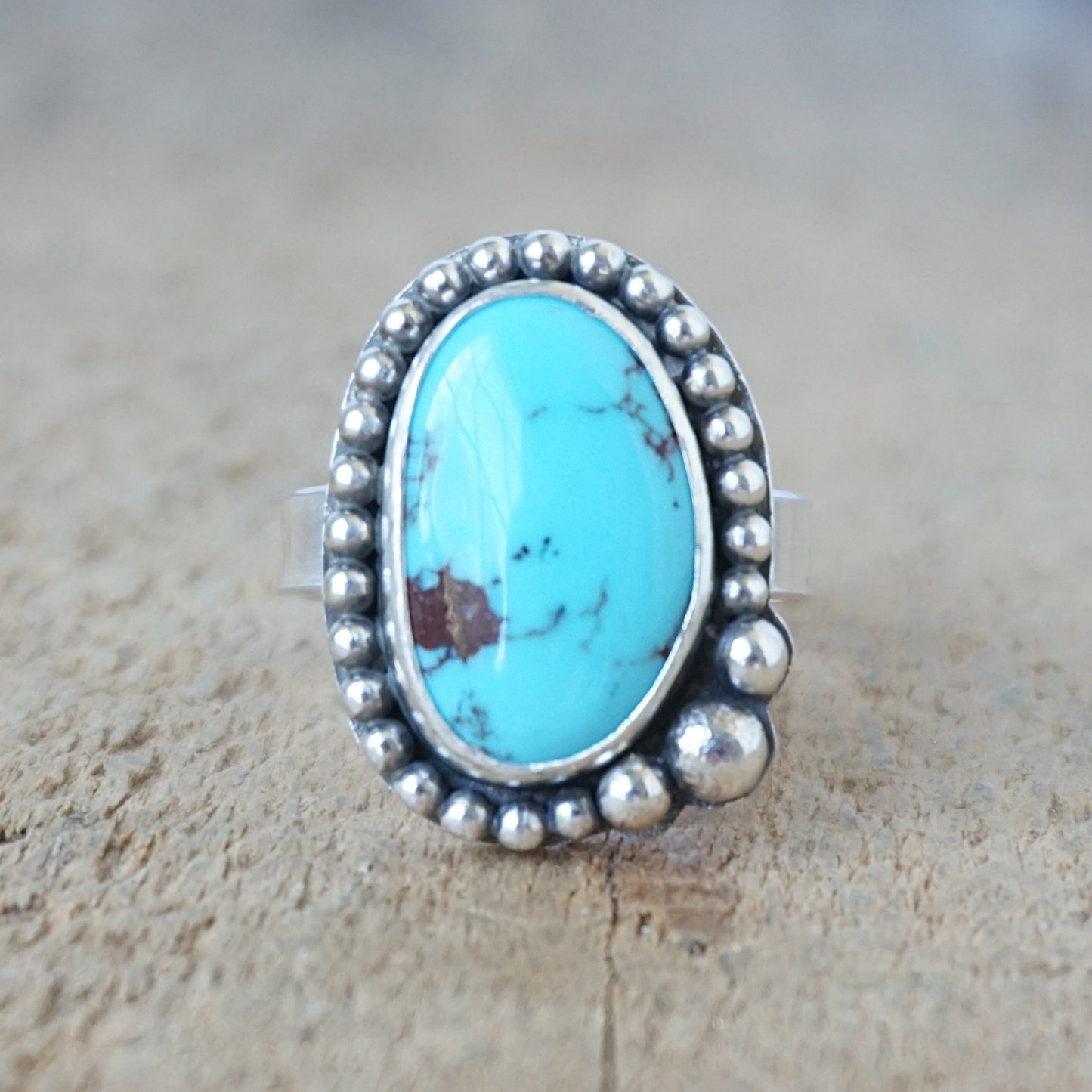 Turquoise ring with silver bezel on a wooden surface