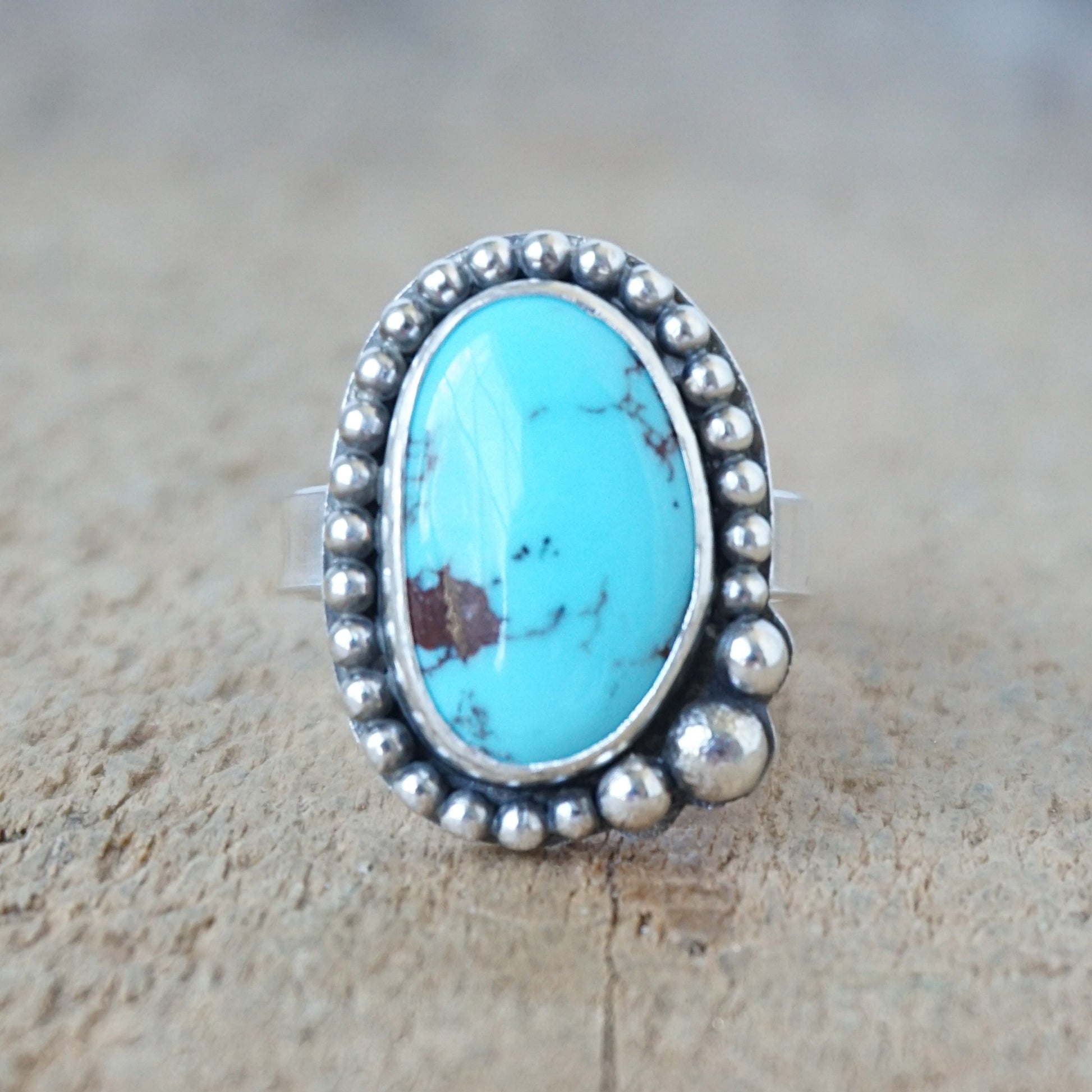 Turquoise ring with silver bezel on a wooden surface