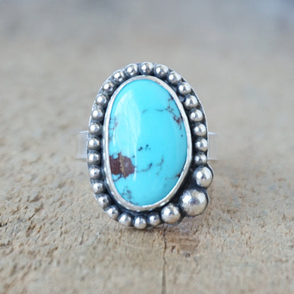 Turquoise ring with silver bezel on a wooden surface