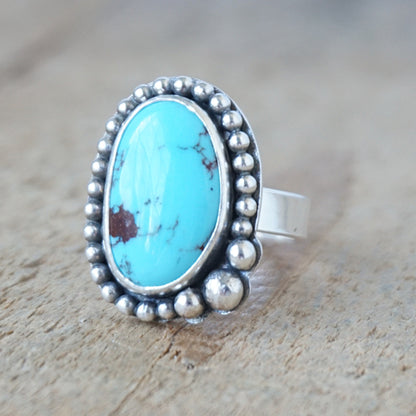 Turquoise ring with silver beaded trim detail on a wooden surface