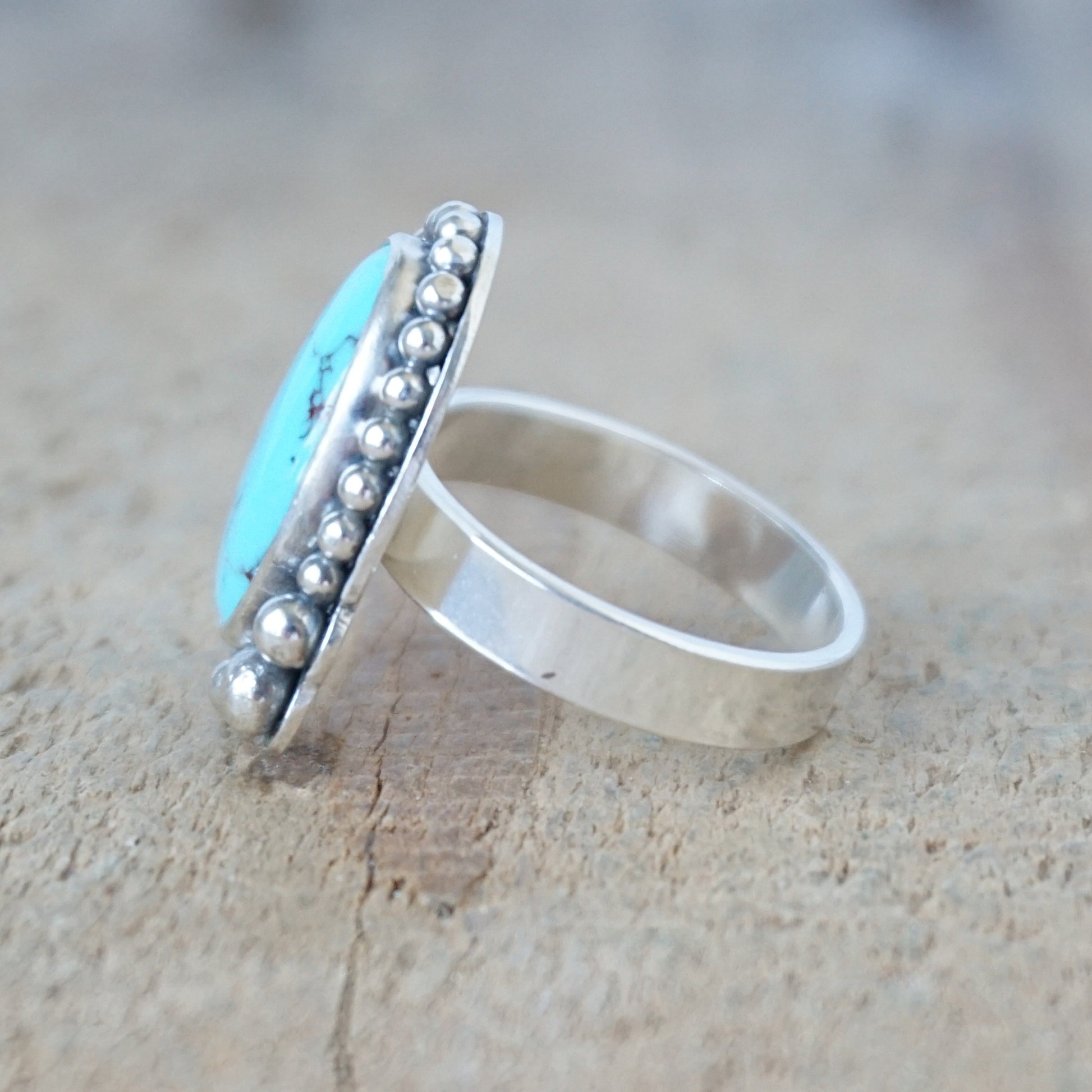 Silver ring with turquoise stone on a wooden surface