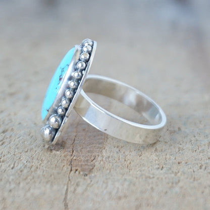 Silver ring with turquoise stone on a wooden surface