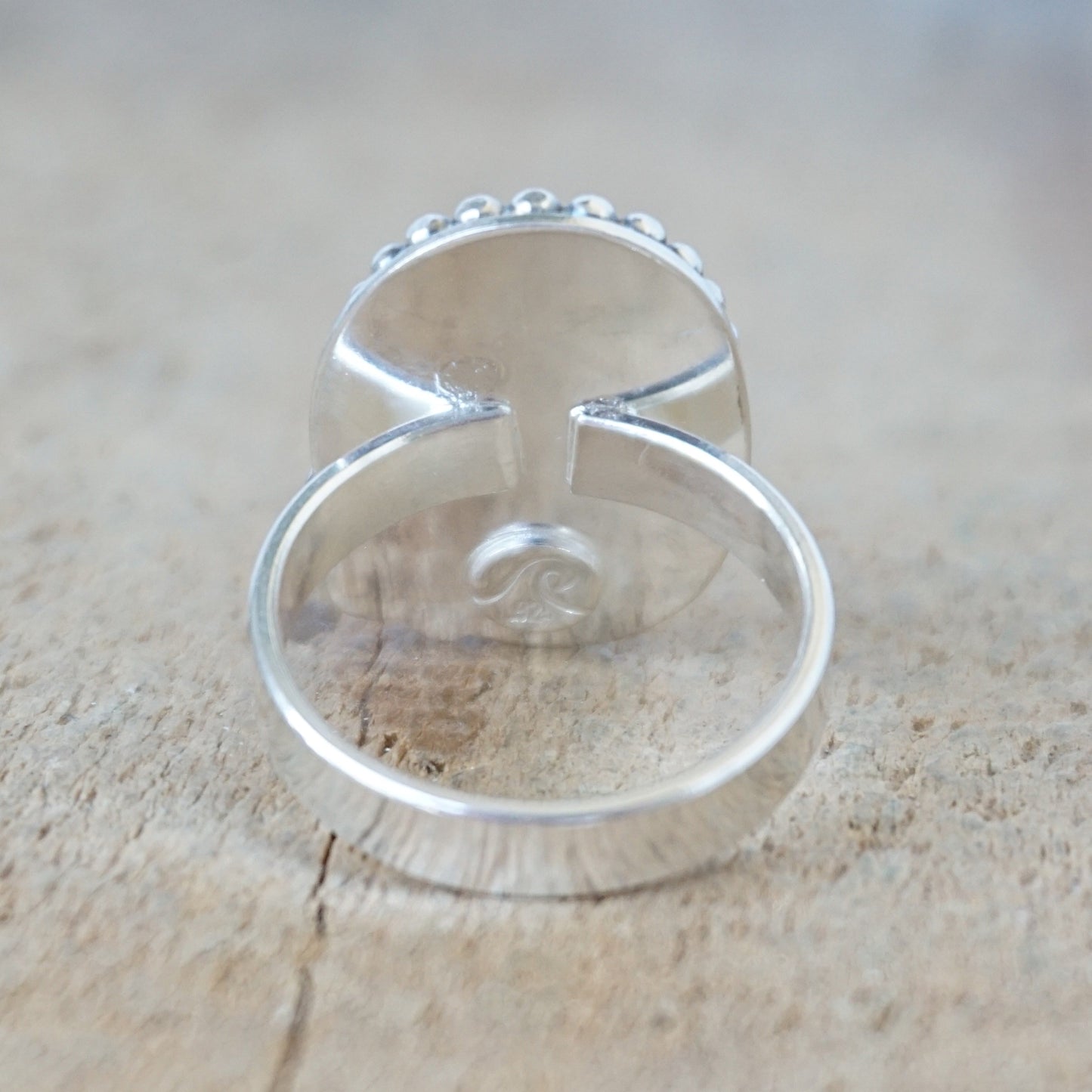 Silver ring with turquoise stone on a wooden surface