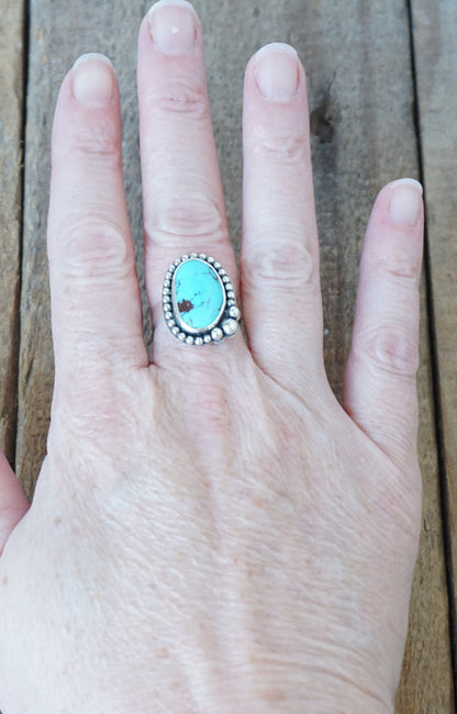Turquoise ring on a hand with a wooden background