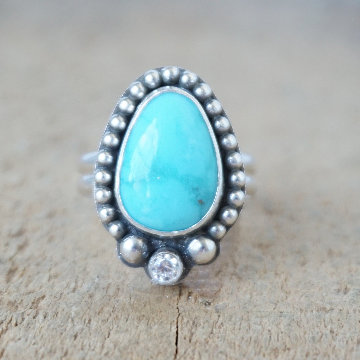 Turquoise ring with silver bezel on a wooden surface