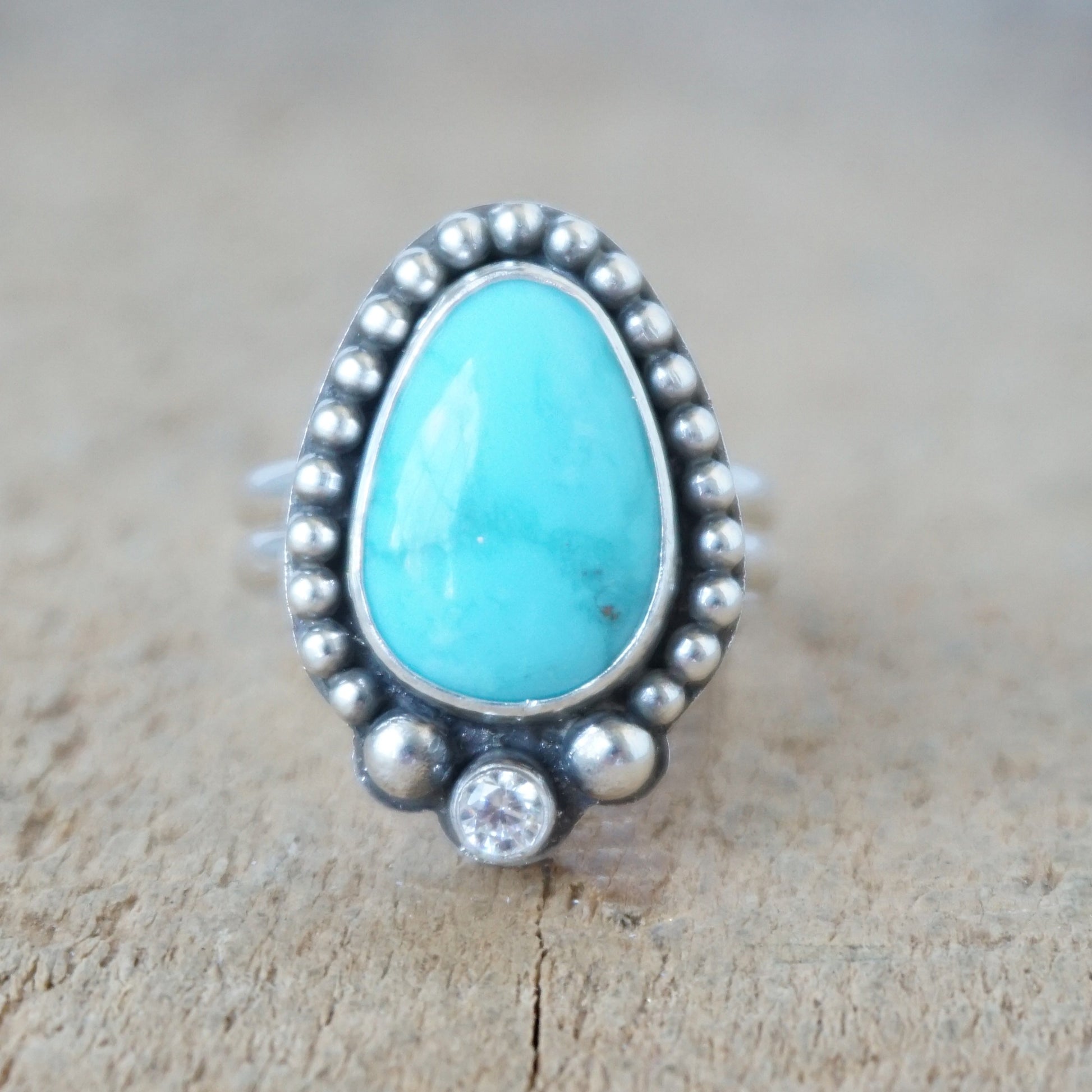 Turquoise ring with silver bezel on a wooden surface