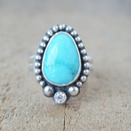 Turquoise ring with silver bezel on a wooden surface