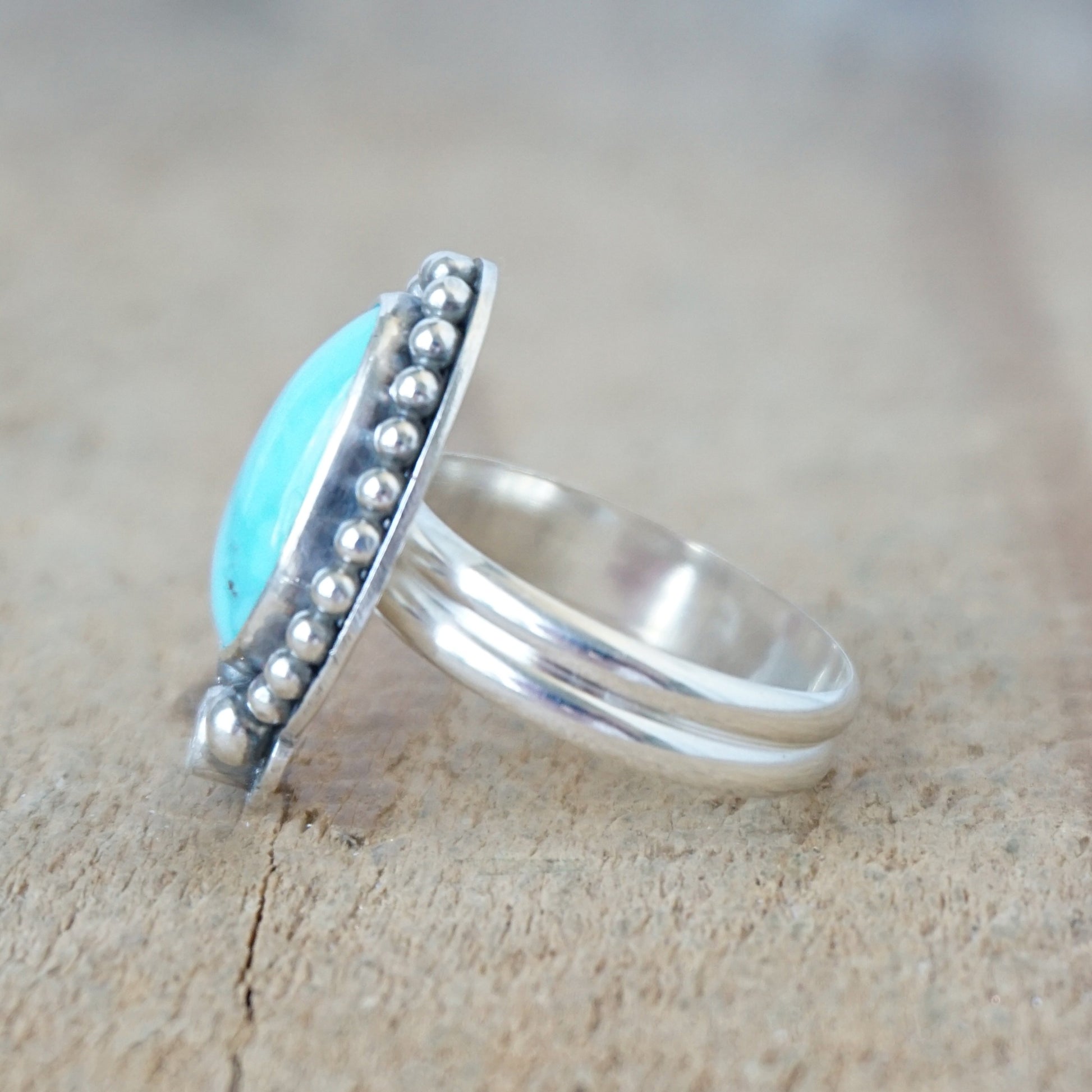 Silver ring with a turquoise stone on a wooden surface