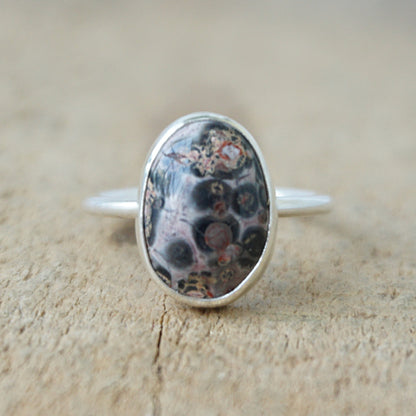 silver ring with a spotted stone on a wooden background