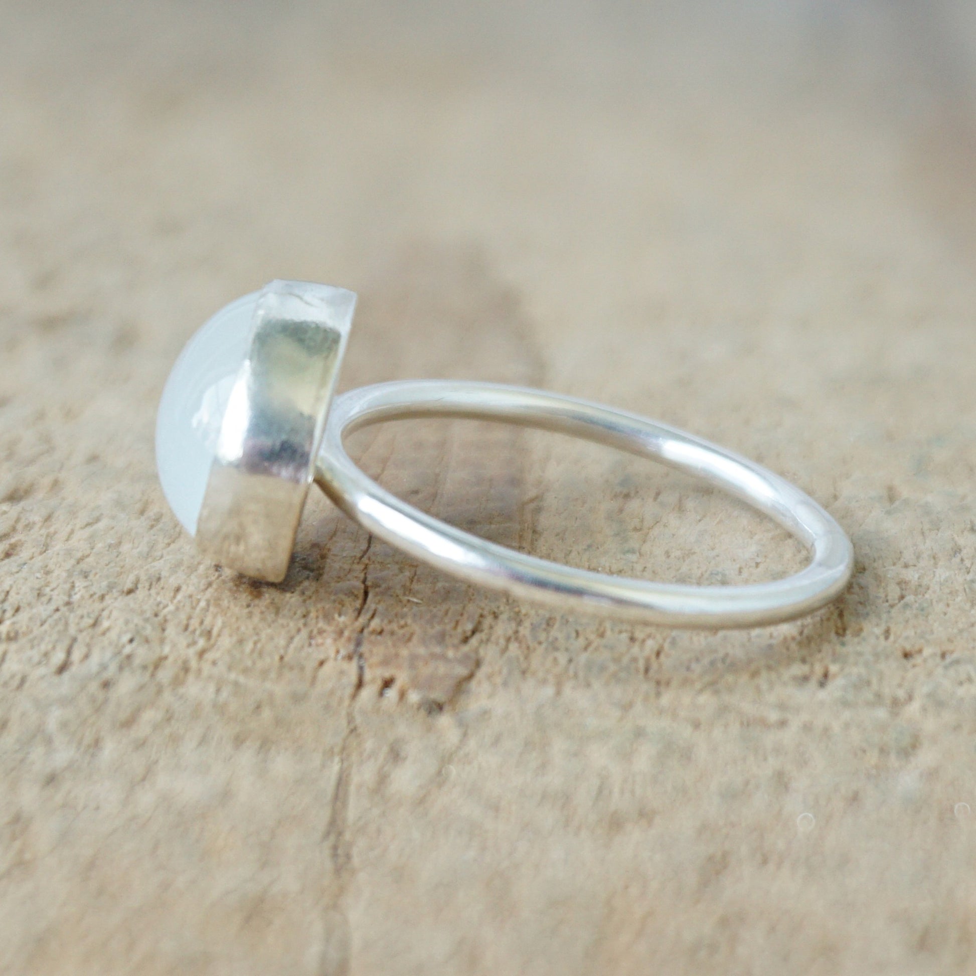 side view of a silver ring with a translucent stone on a wooden background