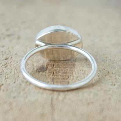 back view of a silver ring with a translucent stone on a wooden background